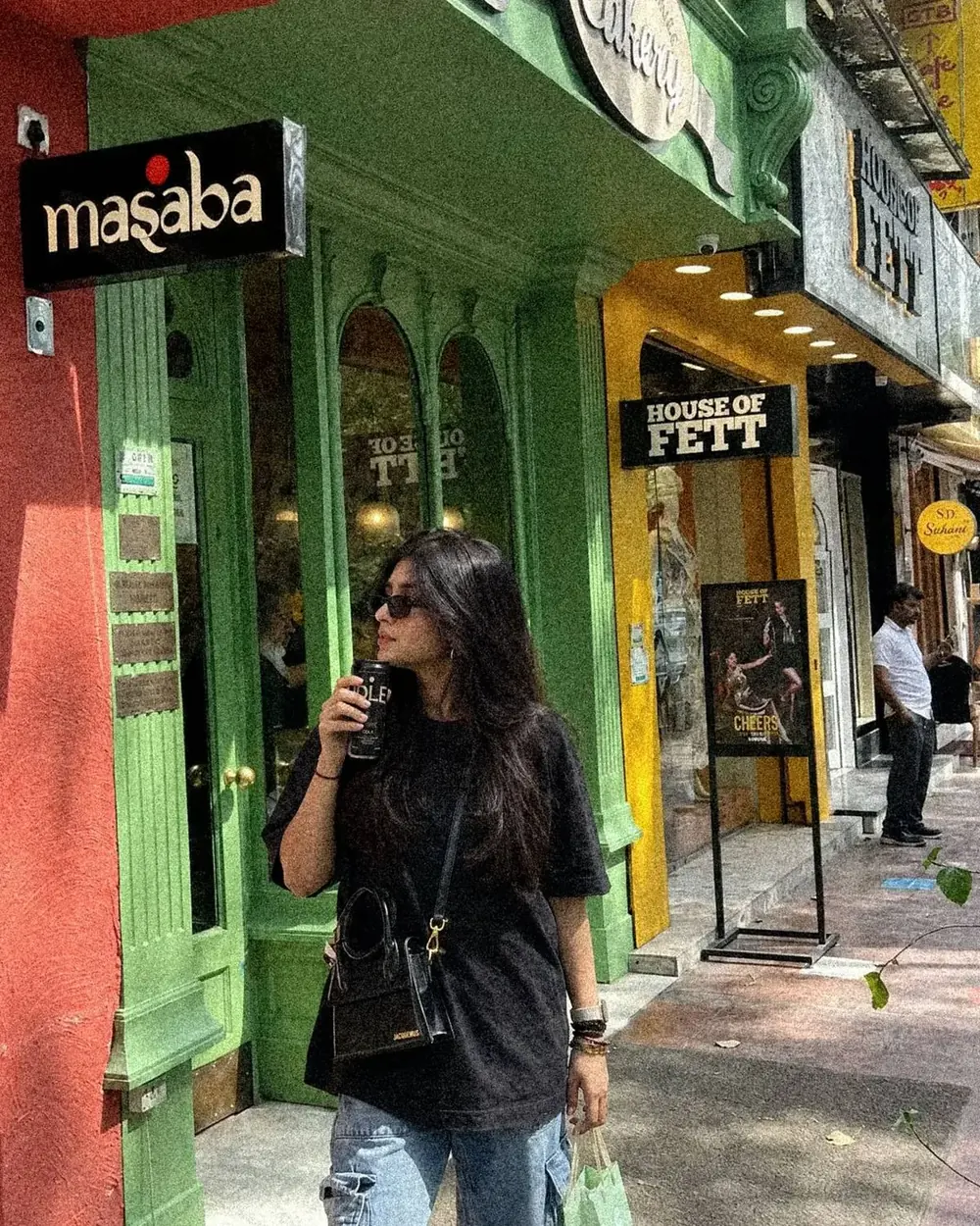 A woman sipping an IDLE Cola on a city street