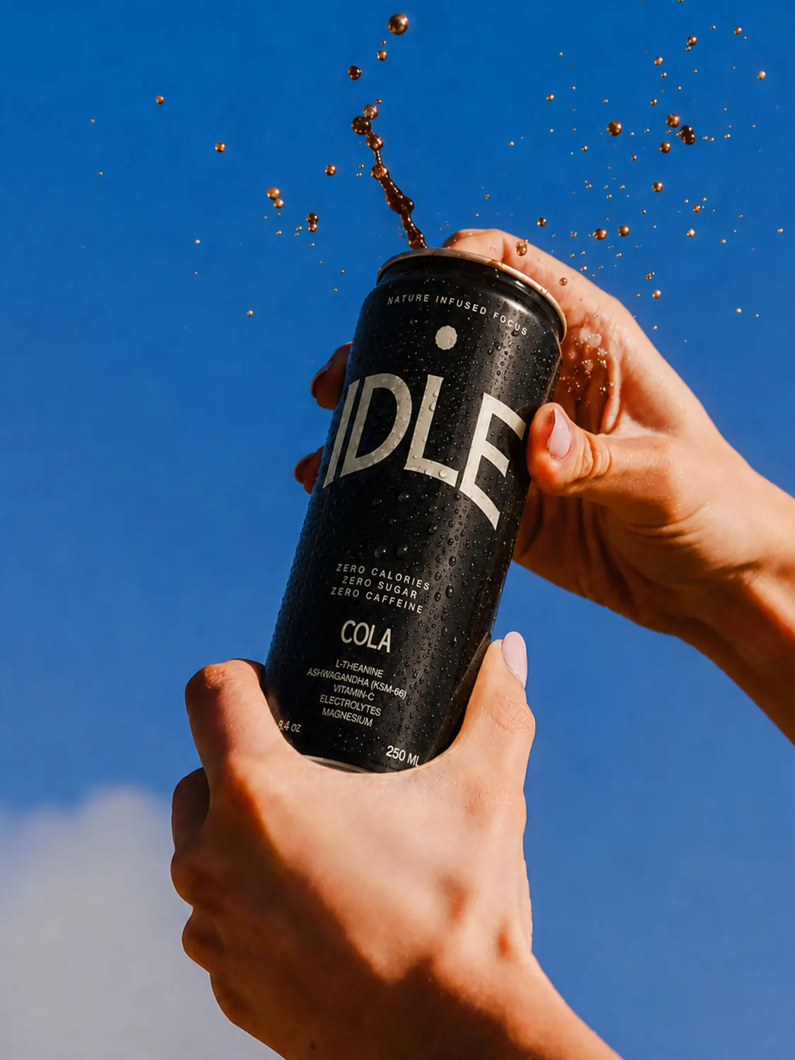A Cola can held up against a blue sky