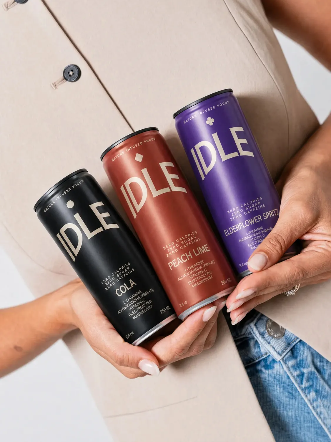 Three hands holding Cola, Peach Lime and Elderflower Spritz cans