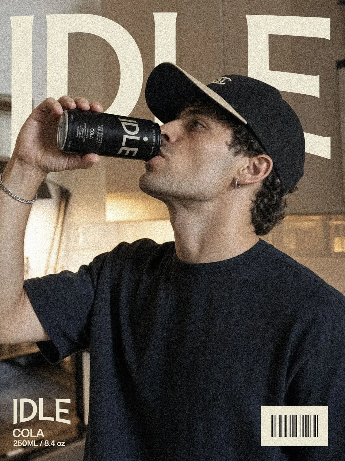 A man in a cap drinking from an IDLE Cola can